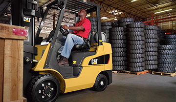 Man Using a Cat Cushion Tire Internal Combustion Forklift to Lift a Load